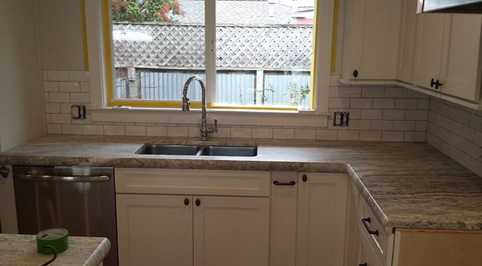 White kitchen with subway backsplash and a tiled counter around the sink.